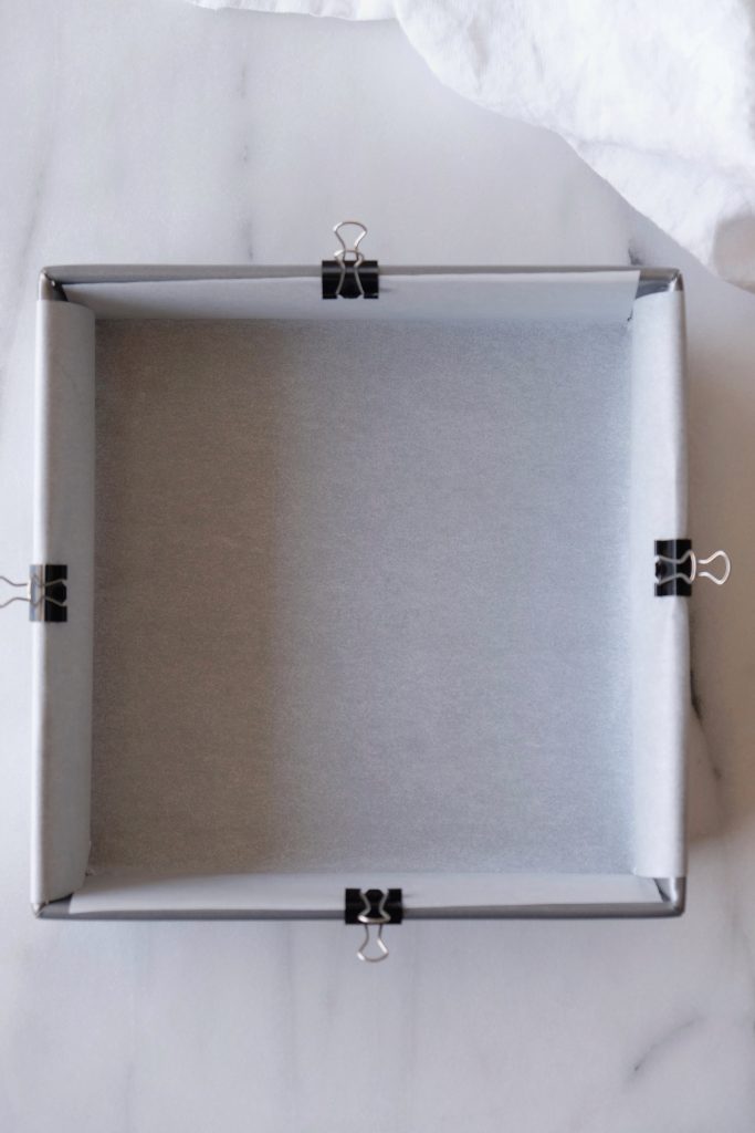 Square baking pan lined with parchment paper