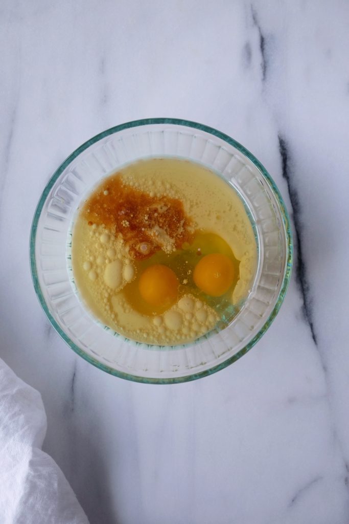 Glass bowl with buttermilk, vegetable oil eggs, vanilla extract