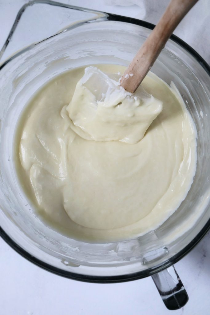 Cheesecake batter in a glass mixing bowl, with a rubber spatula that scraped the sides of the bowl clean