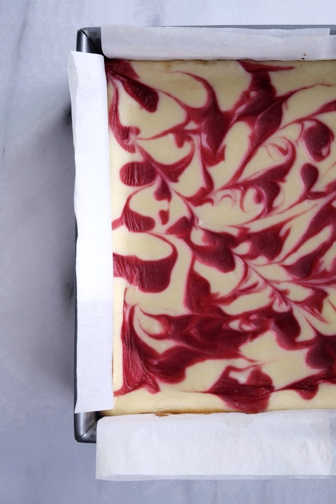 Baked white chocolate raspberry cheesecake in a square baking pan