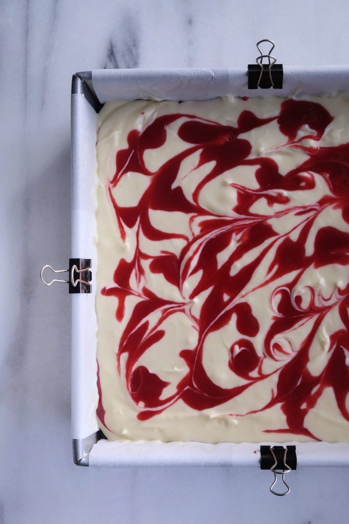 White chocolate raspberry cheesecake in a square baking pan, before it enters the oven