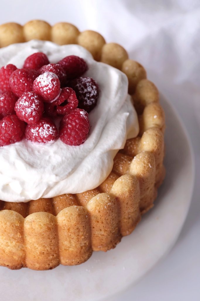 Cream cheese pound cake topped with whipped cream and raspberries